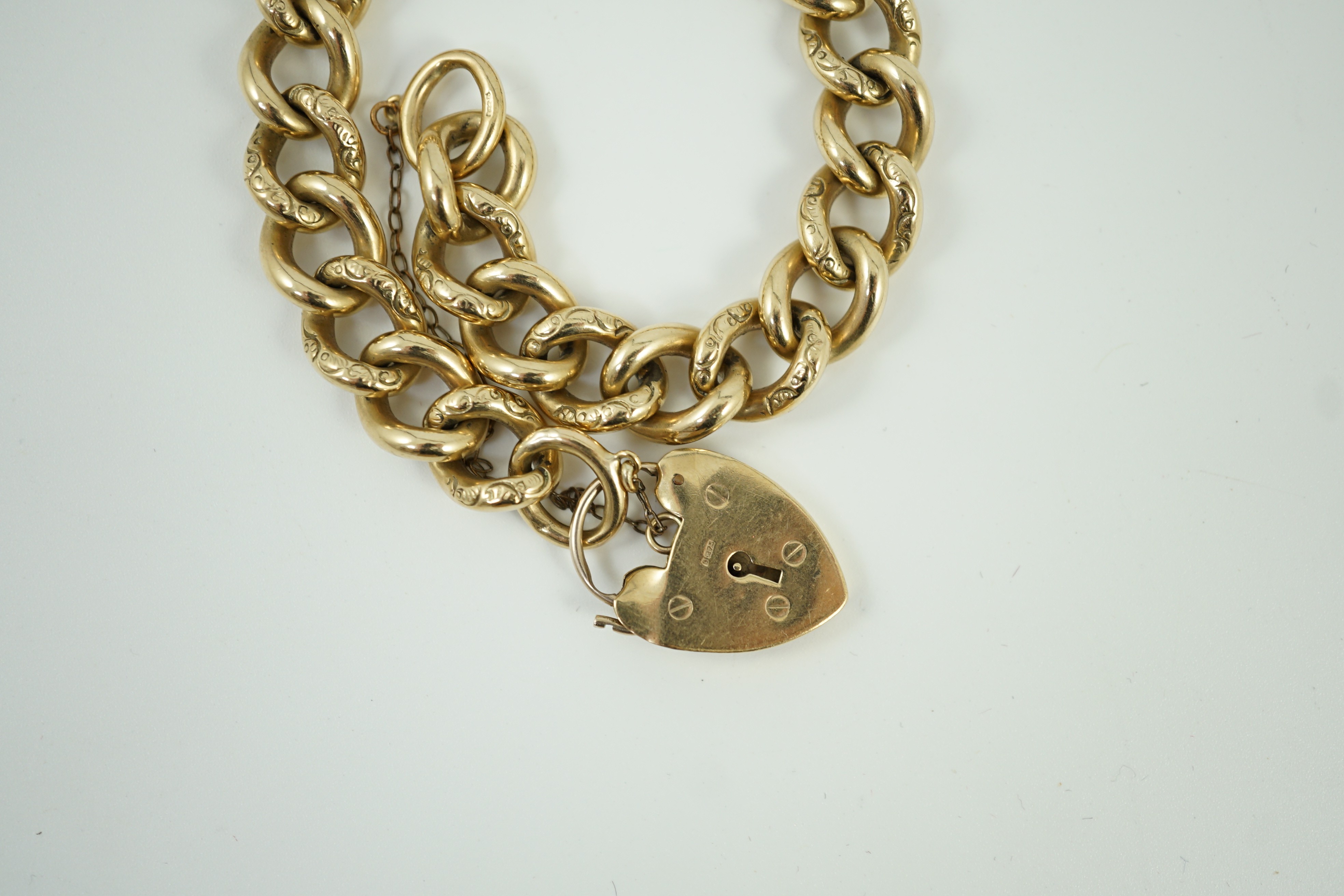 An engraved 9ct gold curb link bracelet, with heart shaped padlock clasp, approx. 18cm, 51.3 grams.